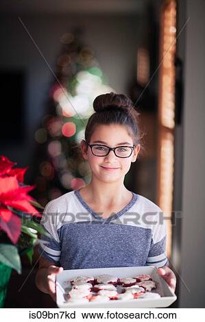 Girl holding tray of homemade christmas cookies in living room, portrait View Large Photo Image Stock Image - Girl holding tray of homemade christmas cookies in living room, portrait. Fotosearch