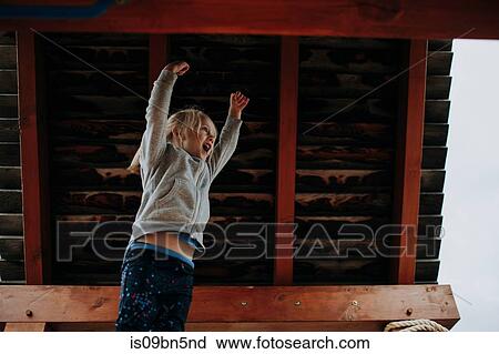 Girl jumping with arms raised on playground platform View Large Photo Image Stock Image - Girl jumping with arms raised on playground platform. Fotosearch