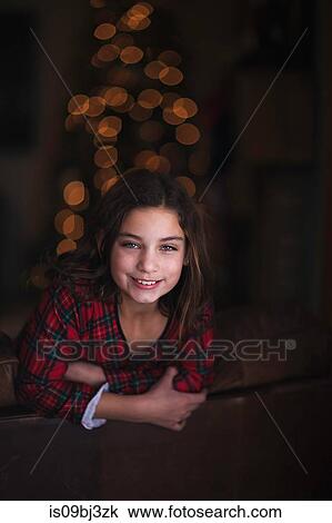 Girl leaning over sofa, smiling, Christmas tree in background View Large Photo Image Stock Image - Girl leaning over sofa, smiling, Christmas tree in background. Fotosearch