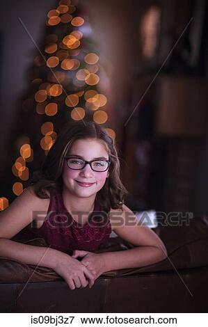 Girl leaning over sofa, smiling, Christmas tree in background View Large Photo Image Stock Photo - Girl leaning over sofa, smiling, Christmas tree in background. Fotosearch