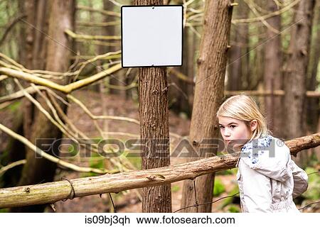 Girl looking back in forest next to blank notice board on tree trunk View Large Photo Image Stock Image - Girl looking back in forest next to blank notice board on tree trunk. Fotosearch