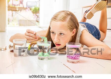 Stock Photo - Girl lying on floor doing experiment with glasses of water. Fotosearch