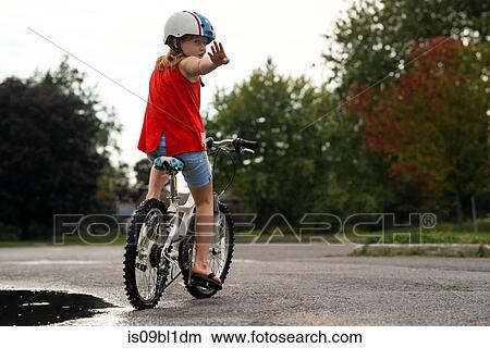 Girl on bicycle stopping in middle of road View Large Photo Image Picture - Girl on bicycle stopping in middle of road. Fotosearch