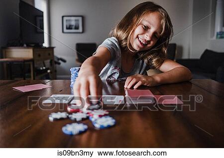 Stock Photo - Girl playing cards at table, placing gambling chips. Fotosearch