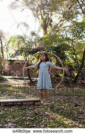 Girl playing with hula hoop in shaded garden View Large Photo Image Stock Photo - Girl playing with hula hoop in shaded garden. Fotosearch