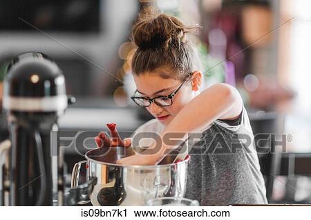 Girl putting ingredients into mixing bowl for christmas cookies at kitchen counter View Large Photo Image Stock Image - Girl putting ingredients into mixing bowl for christmas cookies at kitchen counter. Fotosearch