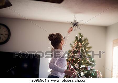 Girl putting up Christmas decorations View Large Photo Image Picture - Girl putting up Christmas decorations. Fotosearch