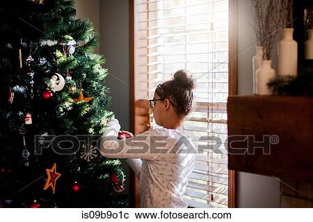 Stock Image - Girl putting up Christmas decorations. Fotosearch