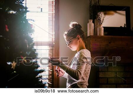 Stock Photo - Girl putting up Christmas decorations. Fotosearch