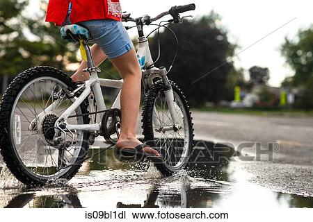Girl riding bicycle on wet road View Large Photo Image Stock Image - Girl riding bicycle on wet road. Fotosearch
