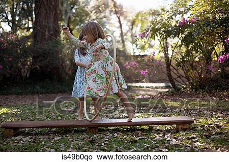 Picture - Girl running through plastic hoop in garden. Fotosearch