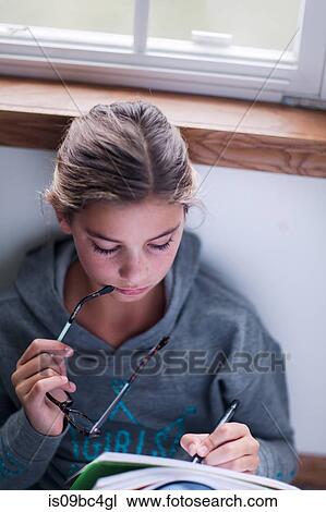 Stock Image - Girl sitting on floor doing homework. Fotosearch