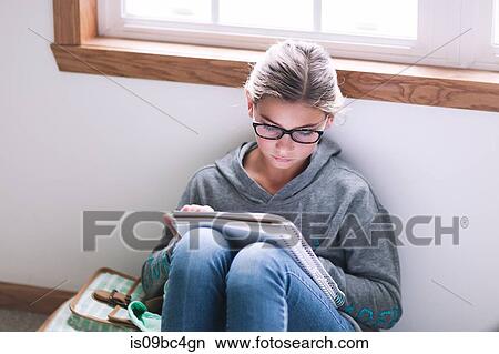 Picture - Girl sitting on floor writing up homework. Fotosearch