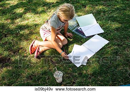 Stock Photo - Girl sitting on grass doing homework. Fotosearch