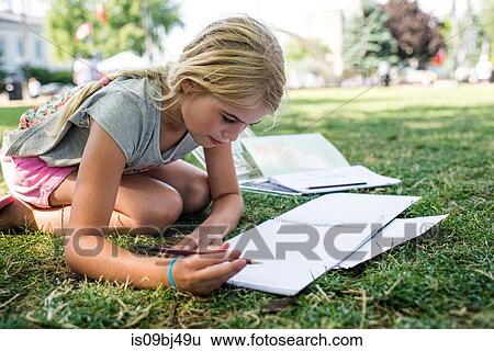 Girl sitting on grass doing homework View Large Photo Image Stock Photograph - Girl sitting on grass doing homework. Fotosearch