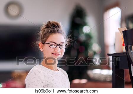 Stock Image - Girl with Christmas tree in background. Fotosearch