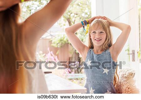 Stock Photograph - Girl with hands behind head smiling, copying sister. Fotosearch