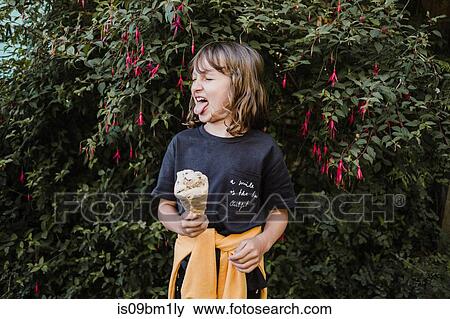 Girl with ice cream cone in front of hedge View Large Photo Image Stock Photo - Girl with ice cream cone in front of hedge. Fotosearch