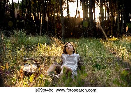 Girl with picnic basket reclining in sunlit forest gazing upward View Large Photo Image Stock Image - Girl with picnic basket reclining in sunlit forest gazing upward. Fotosearch