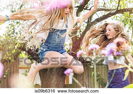 Stock Photograph - Girls in garden jumping in air. Fotosearch