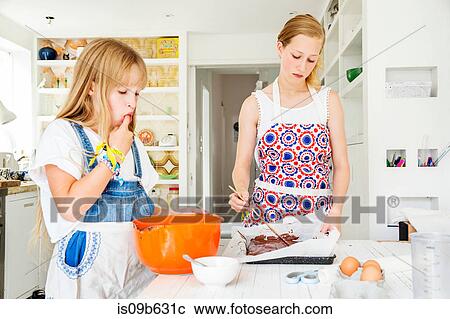 Stock Image - Girls preparing chocolate brownies in kitchen. Fotosearch