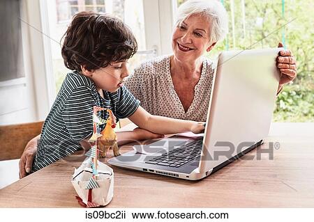 Grandmother and grandson sitting at table, using laptop View Large Photo Image Stock Image - Grandmother and grandson sitting at table, using laptop. Fotosearch