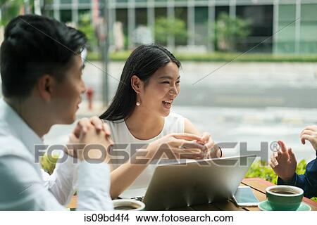 Picture - Group of businesspeople, having meeting at cafe, using laptop, outdoors. Fotosearch