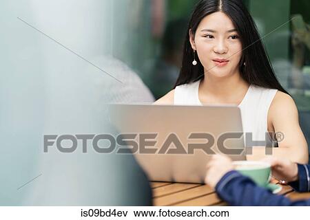 Stock Photo - Group of businesspeople, having meeting at cafe, using laptop. Fotosearch