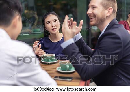 Stock Photography - Group of businesspeople, having meeting at cafe, outdoors. Fotosearch