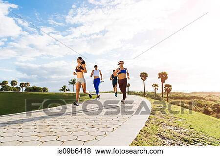 Stock Photo - Group of friends exercising, running, outdoors, low angle view, Point Park, Miami Beach, Florida, USA. Fotosearch