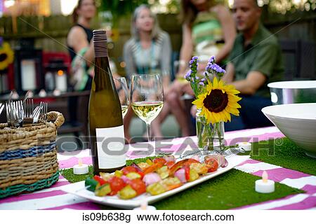 Group of people at garden party, bottle of wine and vegetable kebabs in foreground View Large Photo Image Stock Image - Group of people at garden party, bottle of wine and vegetable kebabs in foreground. Fotosearch