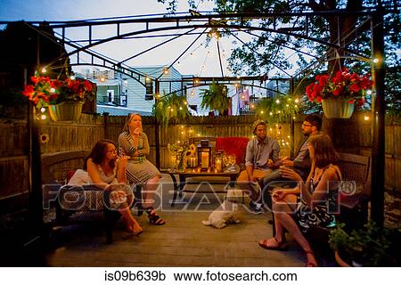 Group of people at garden party, sitting under pergola at dusk, drinking wine View Large Photo Image Stock Image - Group of people at garden party, sitting under pergola at dusk, drinking wine. Fotosearch