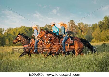 Stock Photograph - Group of people riding horses in field. Fotosearch