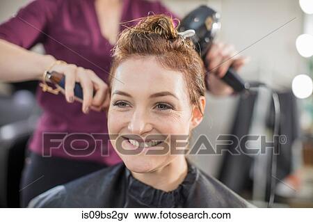 Hairdresser blow drying customer's hair in salon View Large Photo Image Stock Photo - Hairdresser blow drying customer's hair in salon. Fotosearch