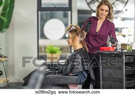 Stock Photography - Hairdresser colouring customer's hair in salon. Fotosearch