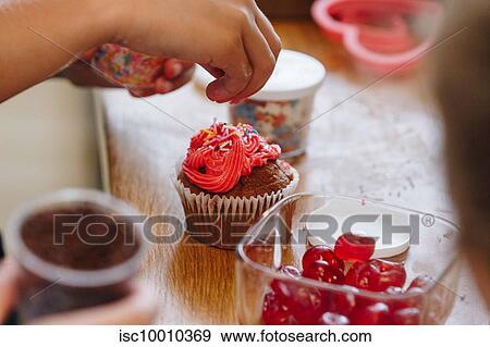 Hand dropping coloured sprinkles onto cupcake View Large Photo Image Stock Photo - Hand dropping coloured sprinkles onto cupcake. Fotosearch
