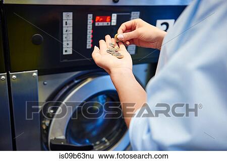 Stock Photograph - Hands of woman selecting coins for washing machine at laundrette. Fotosearch