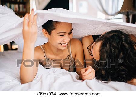 Happy couple under covers in bed View Large Photo Image Picture - Happy couple under covers in bed. Fotosearch