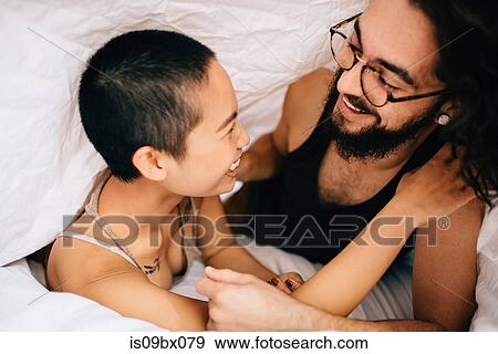 Happy couple under covers in bed View Large Photo Image Stock Photo - Happy couple under covers in bed. Fotosearch