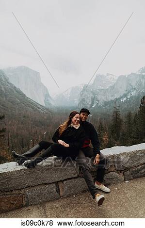 Happy young couple sitting on wall in mountain landscape, Yosemite Village, California, USA View Large Photo Image Stock Photo - Happy young couple sitting on wall in mountain landscape, Yosemite Village, California, USA. Fotosearch