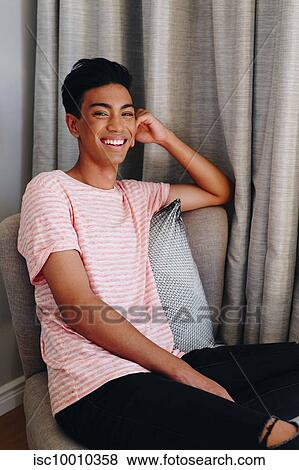 Happy young man sitting on bedroom chair, portrait View Large Photo Image Stock Photo - Happy young man sitting on bedroom chair, portrait. Fotosearch