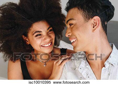 Happy young woman and boyfriend looking at each other in bedroom View Large Photo Image Stock Photography - Happy young woman and boyfriend looking at each other in bedroom. Fotosearch