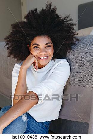 Happy young woman with afro hairstyle sitting on bedroom floor, portrait View Large Photo Image Stock Photo - Happy young woman with afro hairstyle sitting on bedroom floor, portrait. Fotosearch