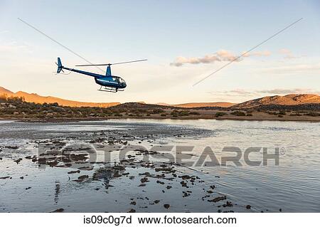 Stock Image - Helicopter flying above watering hole, Cape Town, Western Cape, South Africa. Fotosearch