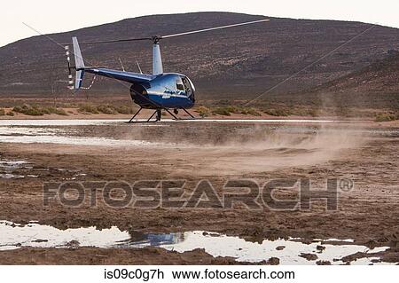 Stock Image - Helicopter hovering above dusty rural landscape, Cape Town, Western Cape, South Africa. Fotosearch