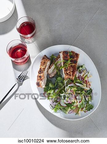 High key still life with glasses of red wine and plate of crisp pork belly and asian salad on white table, overhead view View Large Photo Image Picture - High key still life with glasses of red wine and plate of crisp pork belly and asian salad on white table, overhead view. Fotosearch