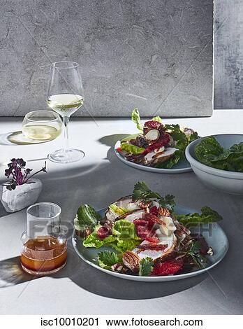 High key still life with glasses of white wine and plates of spiced chicken, blood orange and date salad on white table View Large Photo Image Stock Image - High key still life with glasses of white wine and plates of spiced chicken, blood orange and date salad on white table. Fotosearch