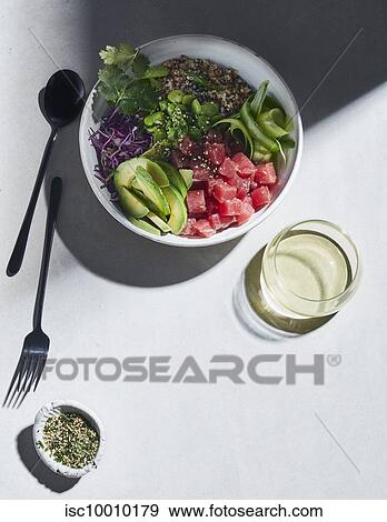 Stock Photo - High key still life with tuna and quinoa poke bowl on white table, overhead view. Fotosearch