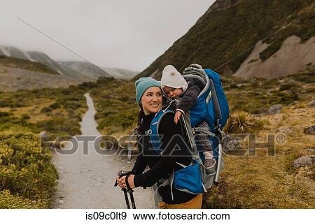 Stock Photo - Hiker and baby exploring trail, Wanaka, Taranaki, New Zealand. Fotosearch