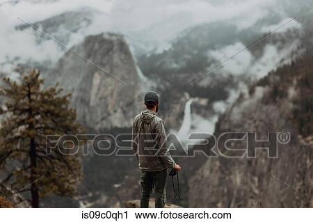 Stock Image - Hiker enjoying view of fog covering valley, Yosemite National Park, California, United States. Fotosearch